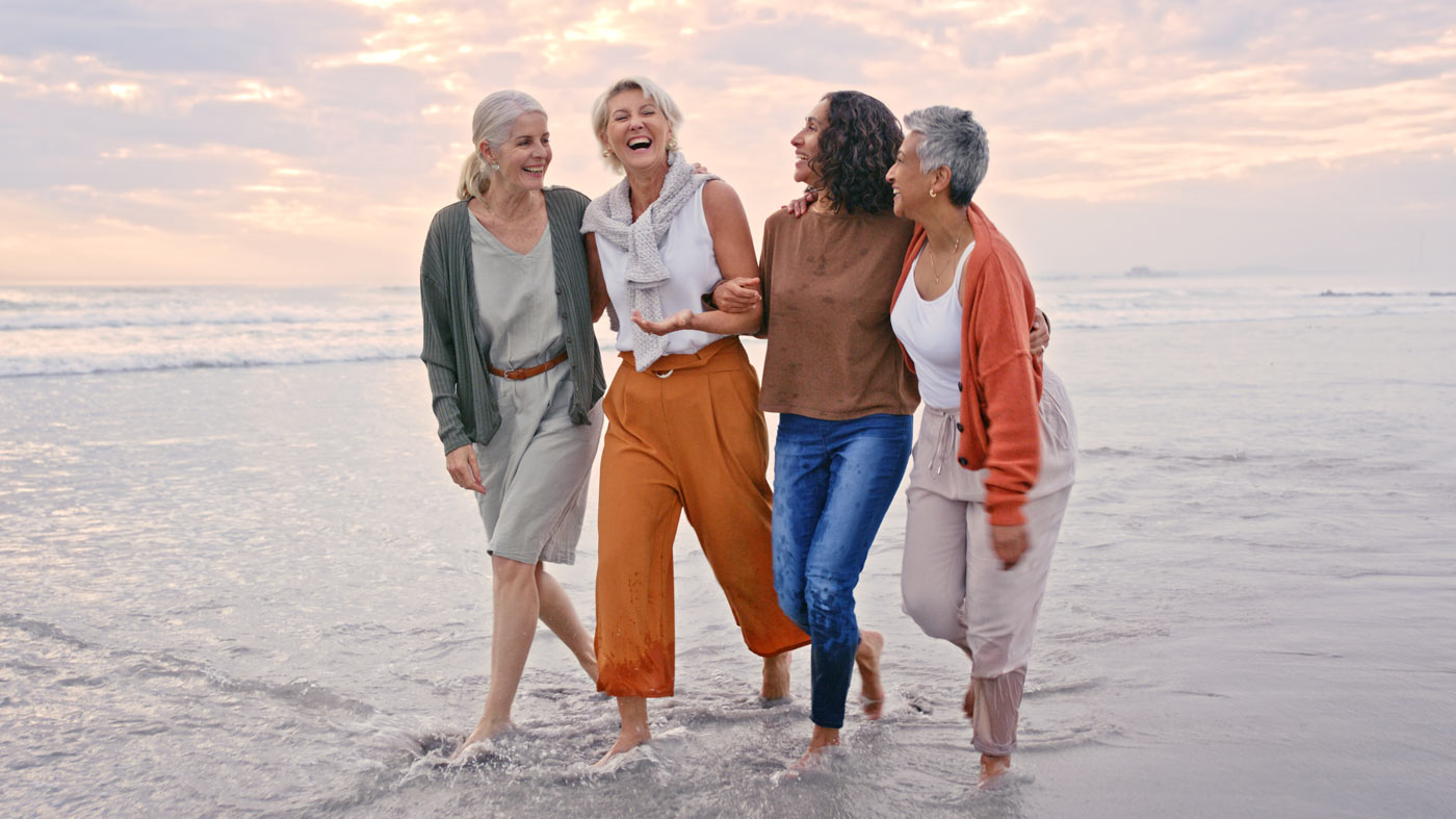 Four women walking together on a beach
